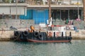 Small harbor workboat moored at quay with tire fenders and deck crane Royalty Free Stock Photo