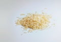 Small heap of uncooked parboiled rice, also called converted rice, on a light gray background, copy space, selected focus