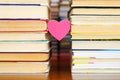 A small heart hangs between two piles of old books. Royalty Free Stock Photo