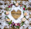 A small heart laid out of snow on a wooden table