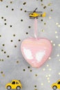 Small helicopter carry large pink heart and small yellow cars on blue background with stars