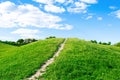 Small hiking trail, path climbing up the mountain, hill, mound with green grass against bright blue sky with clouds Royalty Free Stock Photo