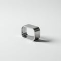 A small, hollow, rectangular metal object with rounded corners rests on a plain light Royalty Free Stock Photo