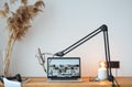 Small home room for podcaster. Voice microphone, laptop and lamp on the wooden table