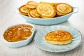 Small pancakes in blue plate, lemon jam in bowl, pancake with lemon jam in saucer on wooden table