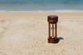 Small hourglass show time is flowing on sand beach background Royalty Free Stock Photo