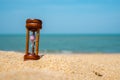 Small hourglass show time is flowing on sand beach background Royalty Free Stock Photo