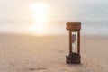 Small hourglass show time is flowing on sand beach background Royalty Free Stock Photo