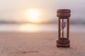 Small hourglass show time is flowing on sand beach background Royalty Free Stock Photo