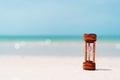 Small hourglass show time is flowing on sand beach background Royalty Free Stock Photo