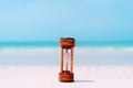 Small hourglass show time is flowing on sand beach background Royalty Free Stock Photo