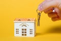 Small house with keys in hand on yellow background Royalty Free Stock Photo
