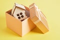 Small house model in a gift box on a yellow background Royalty Free Stock Photo