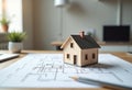 Small house model placed on architectural floor plan on desk in home office Royalty Free Stock Photo