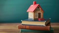 A small house model placed on a stack of books Royalty Free Stock Photo
