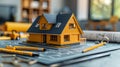 A small house model sits on a blueprint with pencils and tools Royalty Free Stock Photo