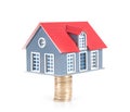 Small house model topped by euro coins on white background Royalty Free Stock Photo