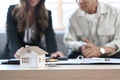 House model on wooden table with Elderly man discussing property purchase with financial advisor in background. Royalty Free Stock Photo