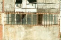 Small house near building with damaged door and walls with bullet holes used as improvised hidden prison with bars on the windows