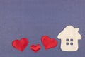 A small house and three red hearts on a gray-blue background. The concept of love, happiness in your home Royalty Free Stock Photo