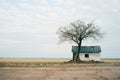 a small house with a tree in the middle of a field Royalty Free Stock Photo