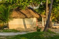 A small hut with a thatched roof sits in a field Royalty Free Stock Photo