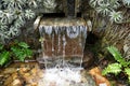 A small indoor waterfall with a single drop by the rocks