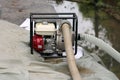 Small industrial petrol water pump with metal frame left on top of improvised sandbags flood protection wall to pump flood water