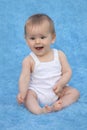 A small infant sits on a blue background and expresses emotions