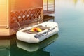 Small inflatable row boat with paddles moored near wooden gazebo on pier. Fishing boat tied at lake or river shore on early Royalty Free Stock Photo