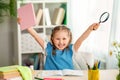 Small inquisitive girl holds up her hands with a book and a magnifying glass