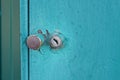 A small iron doorknob and a gray keyhole on a green metal mailbox door