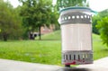 Small iron garbage can in public park with white plastic sign ed Royalty Free Stock Photo