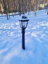 small iron lantern in the park in winter in the snow