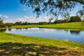 A small irrigation pond with reflections and a green field and hay bales in the background. Royalty Free Stock Photo