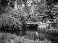 Tranquil scene showing a small decorative iron bridge crossing a still river to a private island.