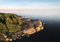 Small island and man with boat, launching drone. Beautiful rocks and cliffs with woods in North Europe, Baltic sea, gulf of