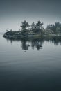 Small island with pine trees lost in the fog. Scenic view Royalty Free Stock Photo