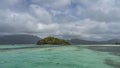 A small island in the turquoise ocean is completely overgrown with tropical vegetation. Royalty Free Stock Photo