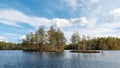 A small islands covered with trees on a forest lake on a sunny windy day against a blue sky with clouds Royalty Free Stock Photo