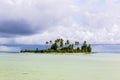 A small islet motu overgrown with palm forest somewhere in the lagoon of Tarawa atoll in bad cloudy weather, Kiribati, Oceania.