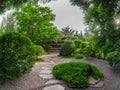 Small Japanese garden park style in spring with trees and wooden house on deep garden. The stone pathway to the house Royalty Free Stock Photo