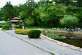 Small Japanese style gazebo in park next to water lilies pond and willow Royalty Free Stock Photo