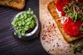 Small jar with basil microgreen sprouts and sandwiches with cream cheese, microgreens, tomato and spices on cutting board. Healthy Royalty Free Stock Photo