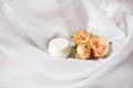 Small jar of expensive anti-aging or anti-wrinkle face cream with delicate roses on white cloth background Royalty Free Stock Photo