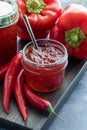 A small jar of homemade red hot pepper jelly surrounded by red peppers Royalty Free Stock Photo