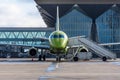 Small jet passenger plane with a ramp parked at the airport against the background of the terminal building Royalty Free Stock Photo