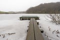 Small jetty on a frozen lake with forest