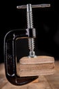 A small joinery clamp used for gluing planks. Accessories for carpenters on the workshop table Royalty Free Stock Photo