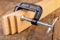 A small joinery clamp used for gluing planks. Accessories for carpenters on the workshop table Royalty Free Stock Photo